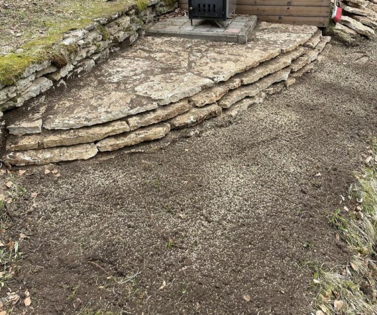 Värskelt paigaldatud muld terrassi ääres, kivist tugiseina kõrval - Saku Ehitus mulla müük ja haljastusteenused.